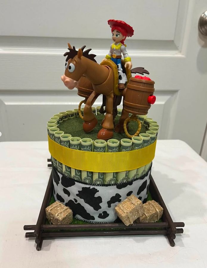 Cowgirl and pony themed money cake with hay bales and a cow-print band